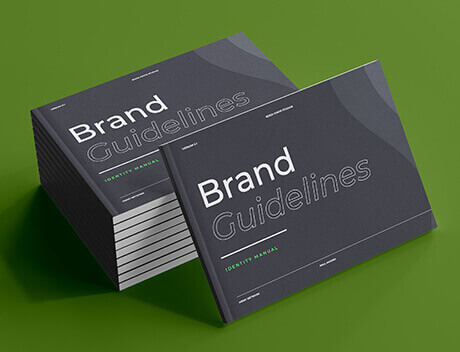 A stack of brand guidelines books with gray covers rests elegantly on a green surface, subtly reflecting the meticulous craftsmanship akin to Conte Studios' renowned work as a leading content creation agency in Toronto. Conte Studios