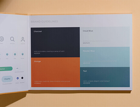 An open book displays brand guidelines for a Toronto Design Agency, featuring color palettes like Charcoal, Cloud Blue, Orange, Powder Blue, and Teal. Each hue comes with descriptions and hex codes. Conte Studios