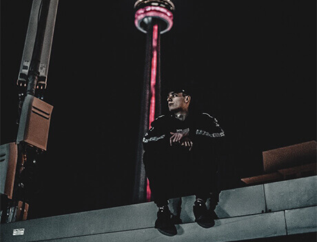 Sitting on a ledge at night, gazing into the distance, a person finds solace while the illuminated tower behind them paints a perfect backdrop—an inspiration for Conte Studios, a premier content creation agency in Toronto. Conte Studios