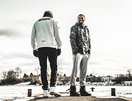 On a snowy dock, two people share a moment. One in a white jacket looks towards the serene lake, while the other, donning a camo jacket, beams at the camera. It's as if Conte Studios captured this scene perfectly—a reflection of their Toronto Design Agency's keen eye for detail and emotion. Conte Studios