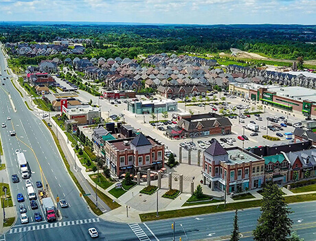 Aerial view of a suburban shopping center with several stores and a parking lot, nestled near residential neighborhoods and intersecting roads, showcasing the vibrant area where Web Design Agency Toronto thrives amidst community life. Conte Studios