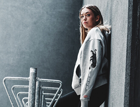 A person in a gray hoodie leans against a wall next to metal bike racks outside Conte Studios, a renowned Toronto Design Agency. Conte Studios